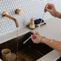 the clear glass straw being cleaned with the cleaner tool